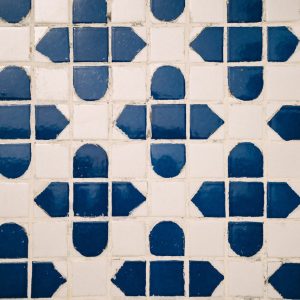 Detailed geometric pattern of blue and white floor tiles captured from above.