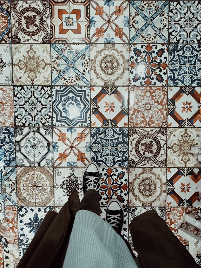 Overhead view of converse sneakers on vibrant patterned tiled floor, showing intricate designs.